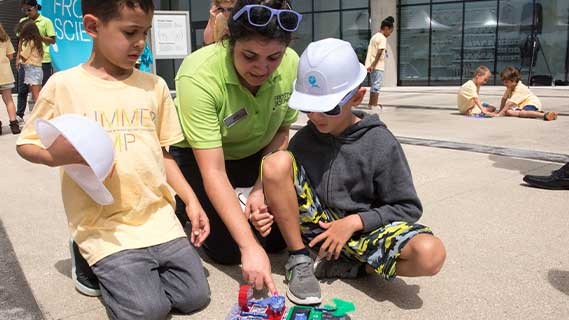 A teacher working with two students outside